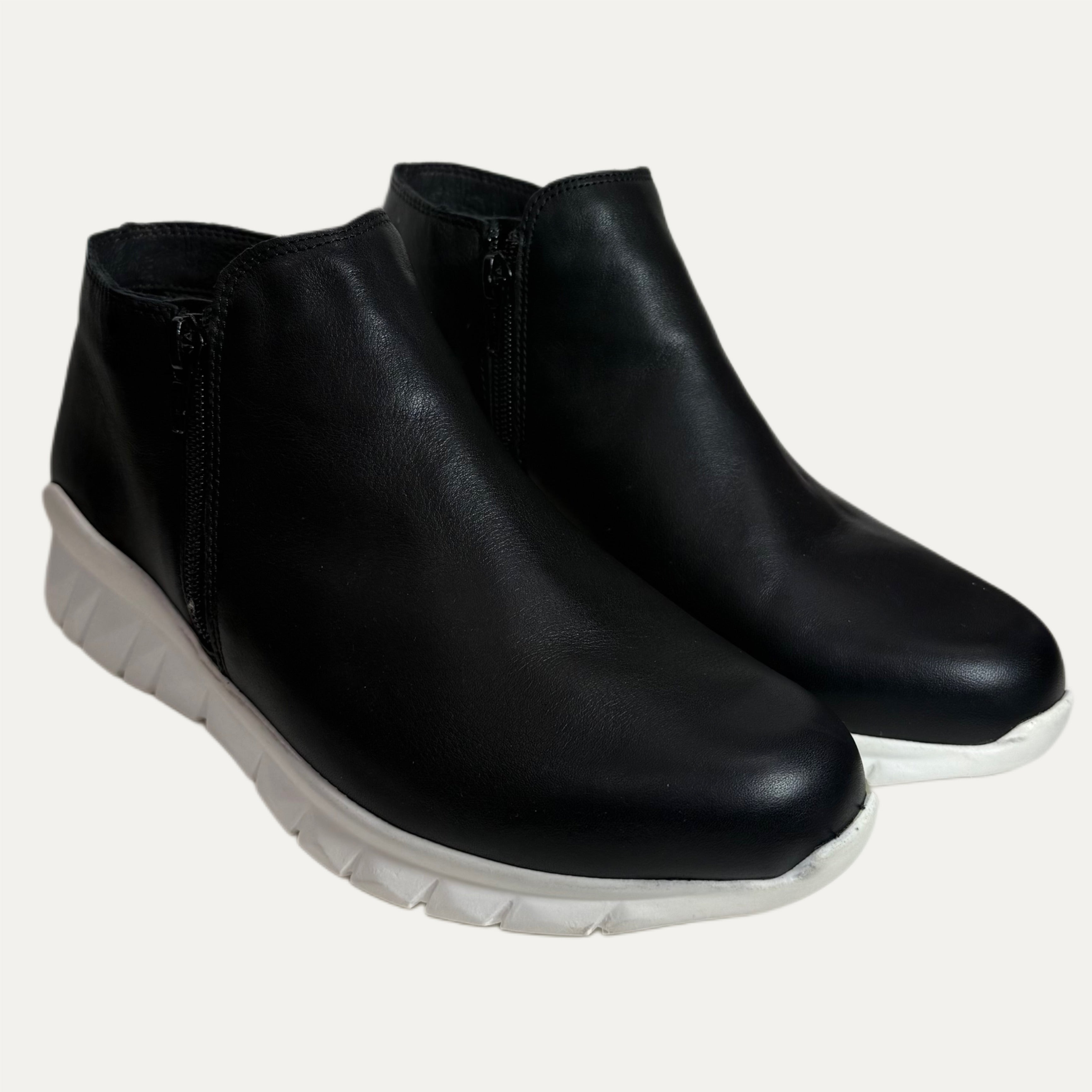 Pair of black ankle boots with white soles on a white background