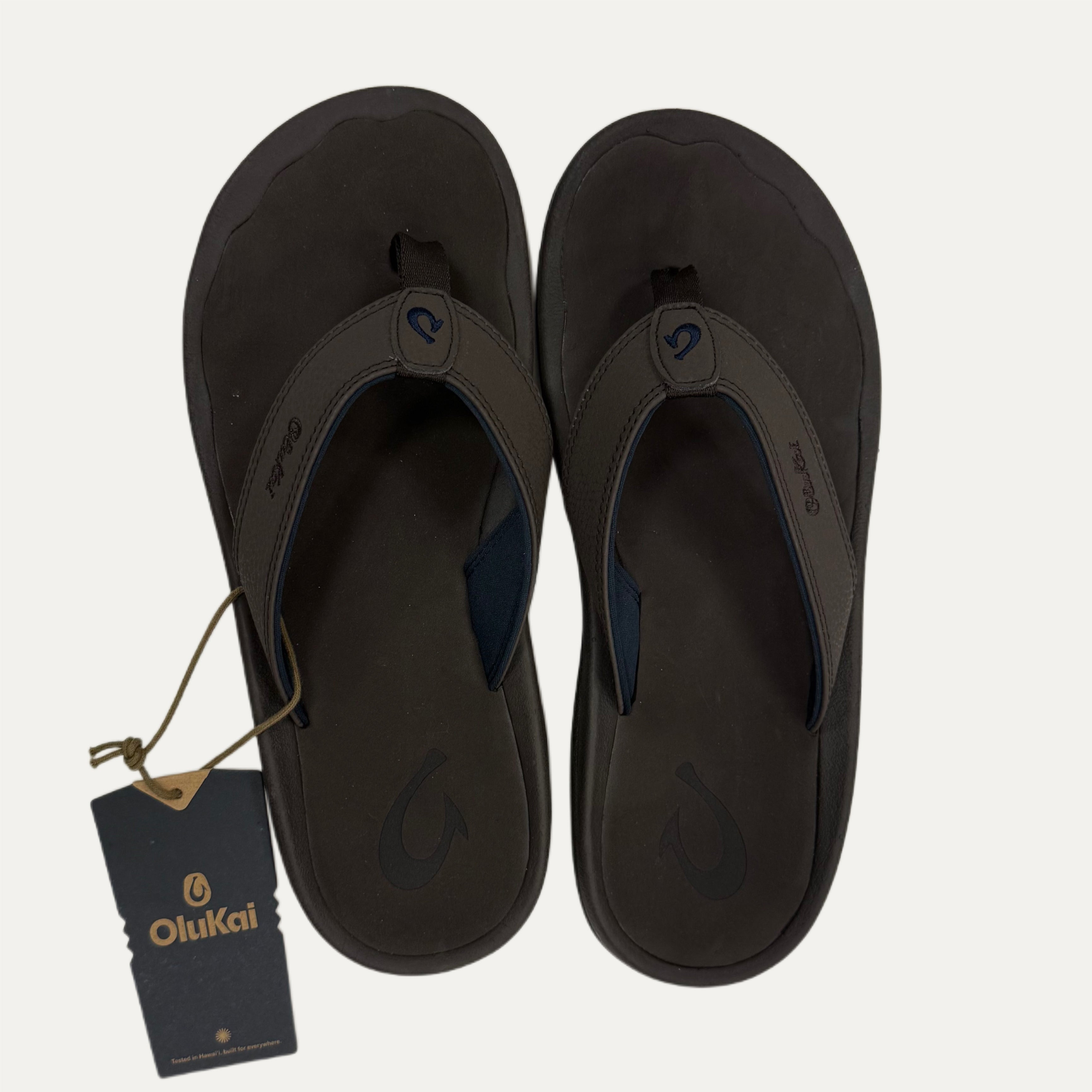 Pair of dark brown flip flops with a visible brand tag.