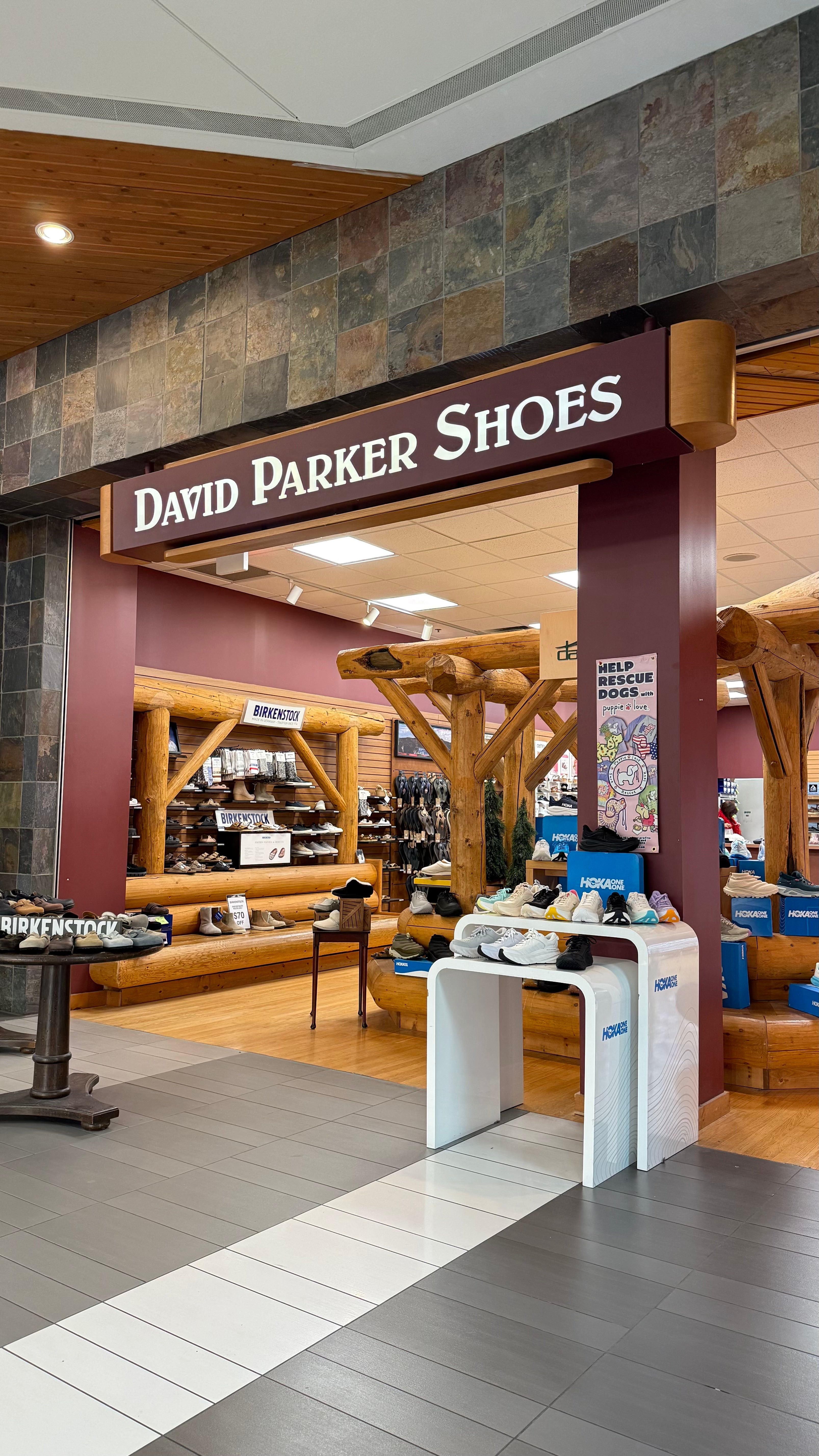 David Parker Shoes store interior with wooden floors and a stone wall.