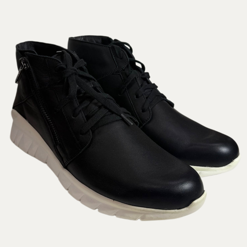 Pair of black leather boots with white soles on a white background
