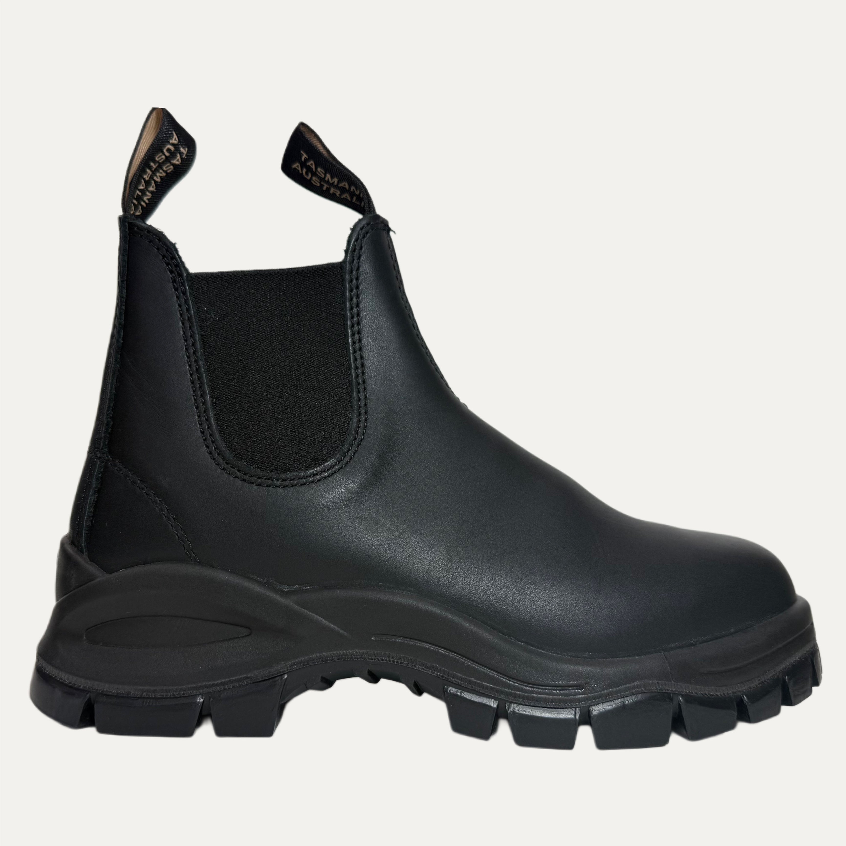 Black lugged leather Chelsea boot with thick sole on a light gray background