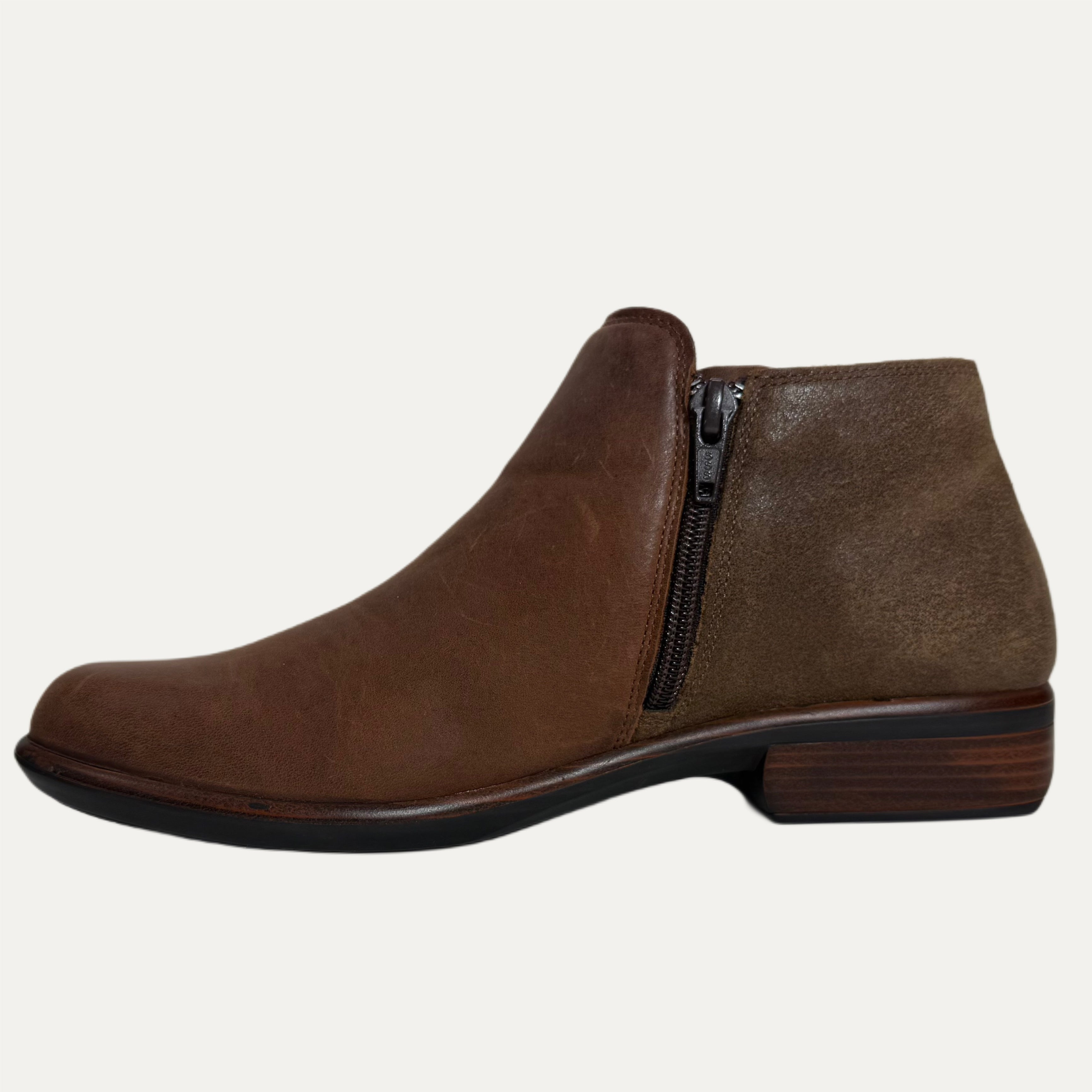 Brown leather ankle boot with a zipper on a light gray background
