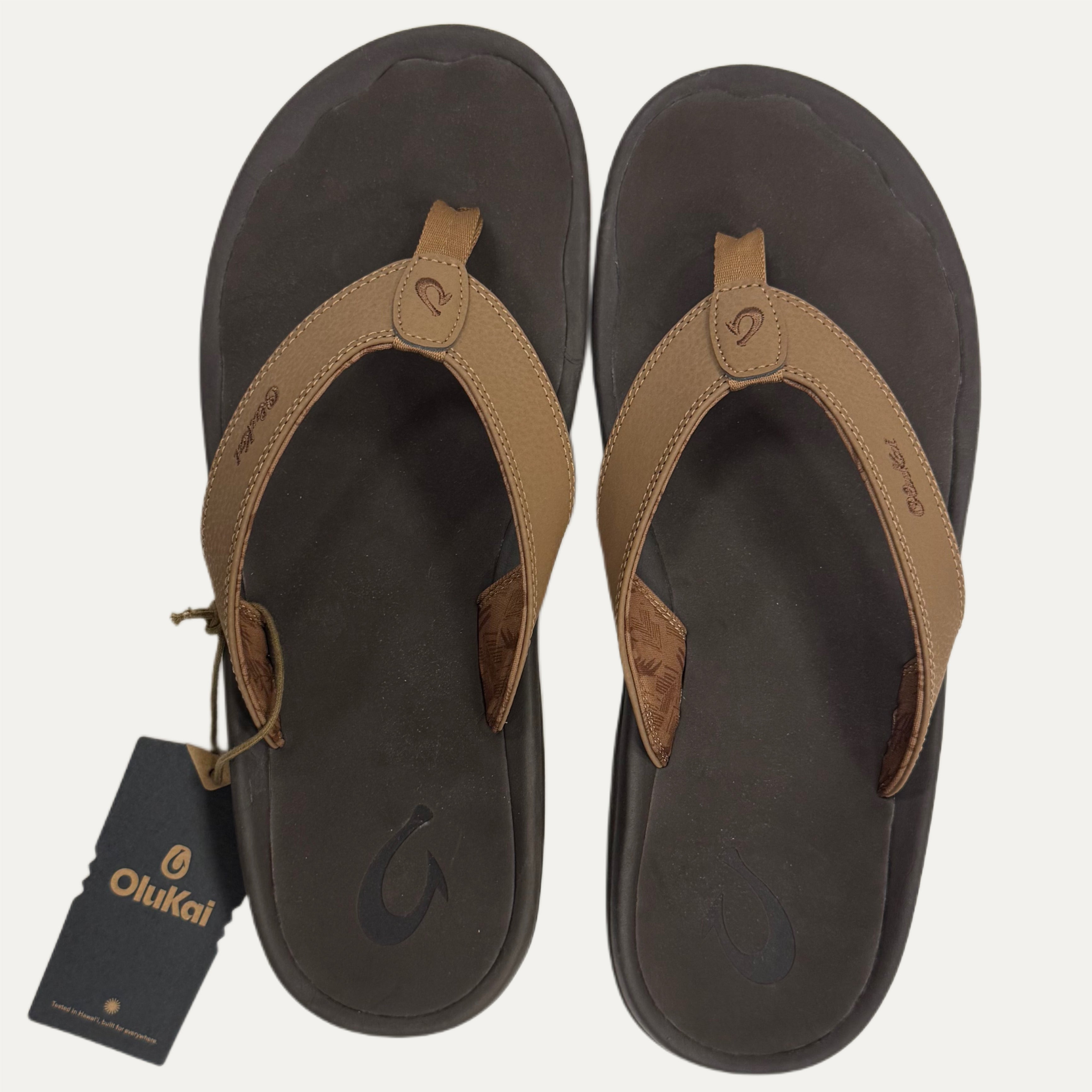 Pair of brown flip flops with a visible brand tag on a white background
