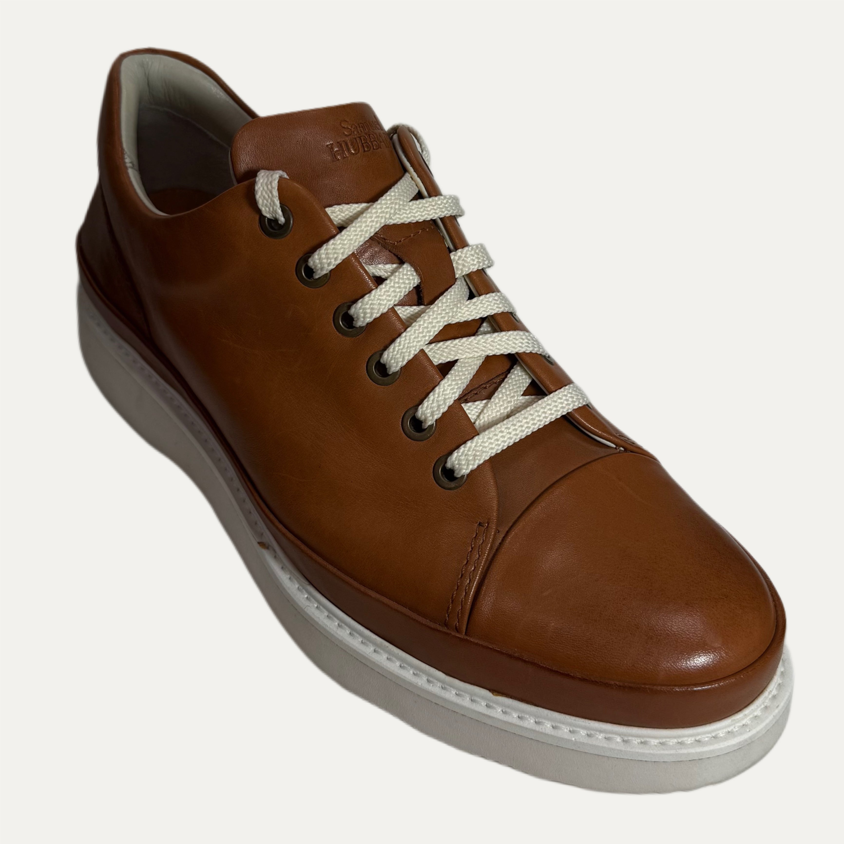Brown leather casual shoe with white laces on a light gray background