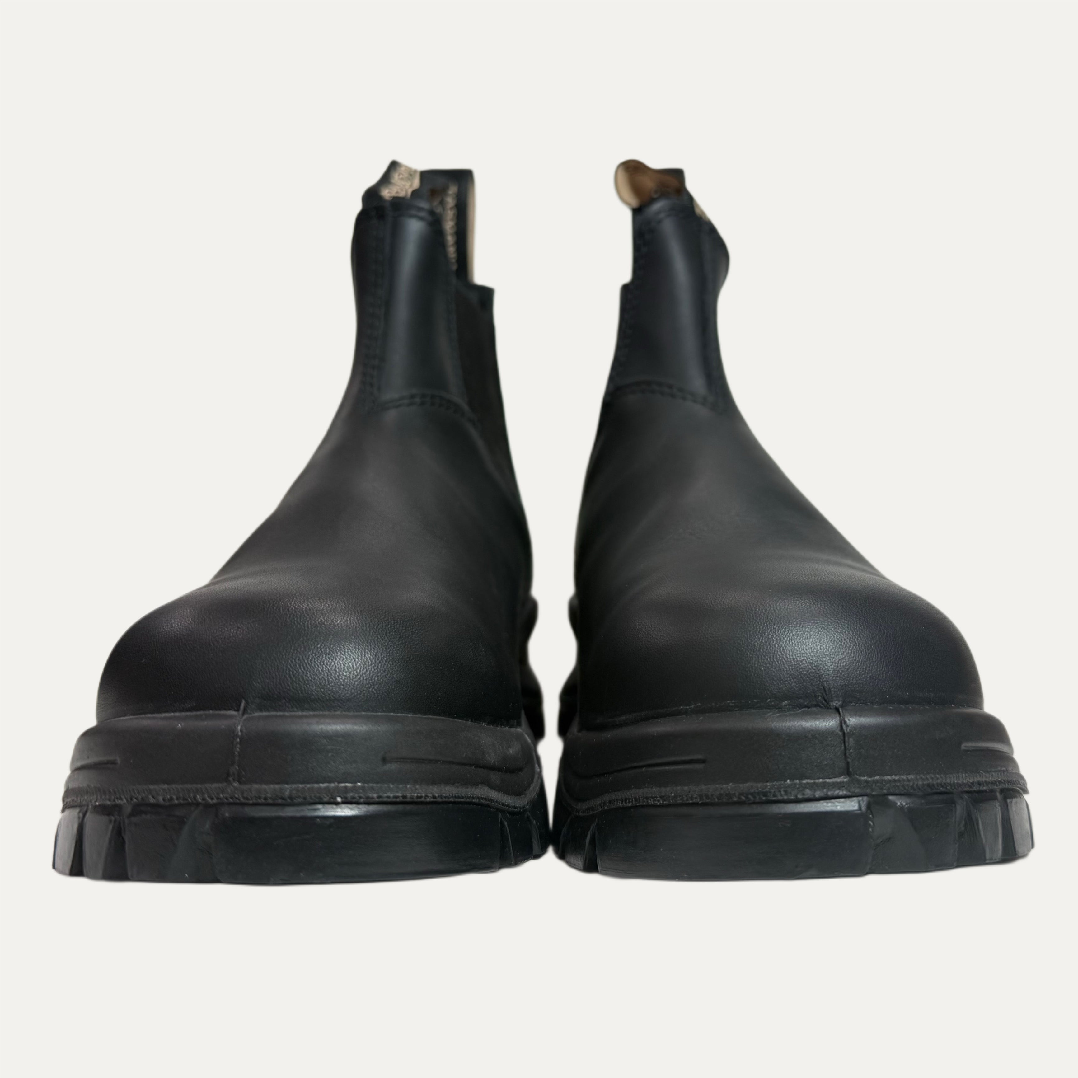 Pair of black leather lugged boots on a light gray background