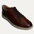 Brown leather shoe with black laces on a white background