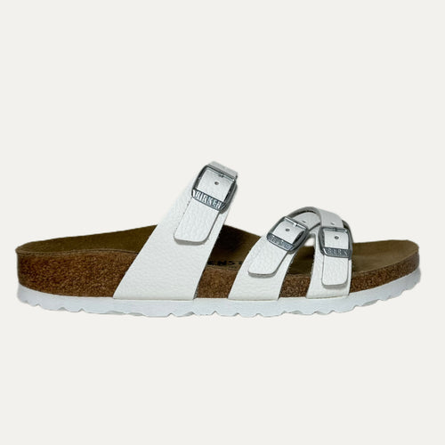 White sandal with brown sole on a light gray background