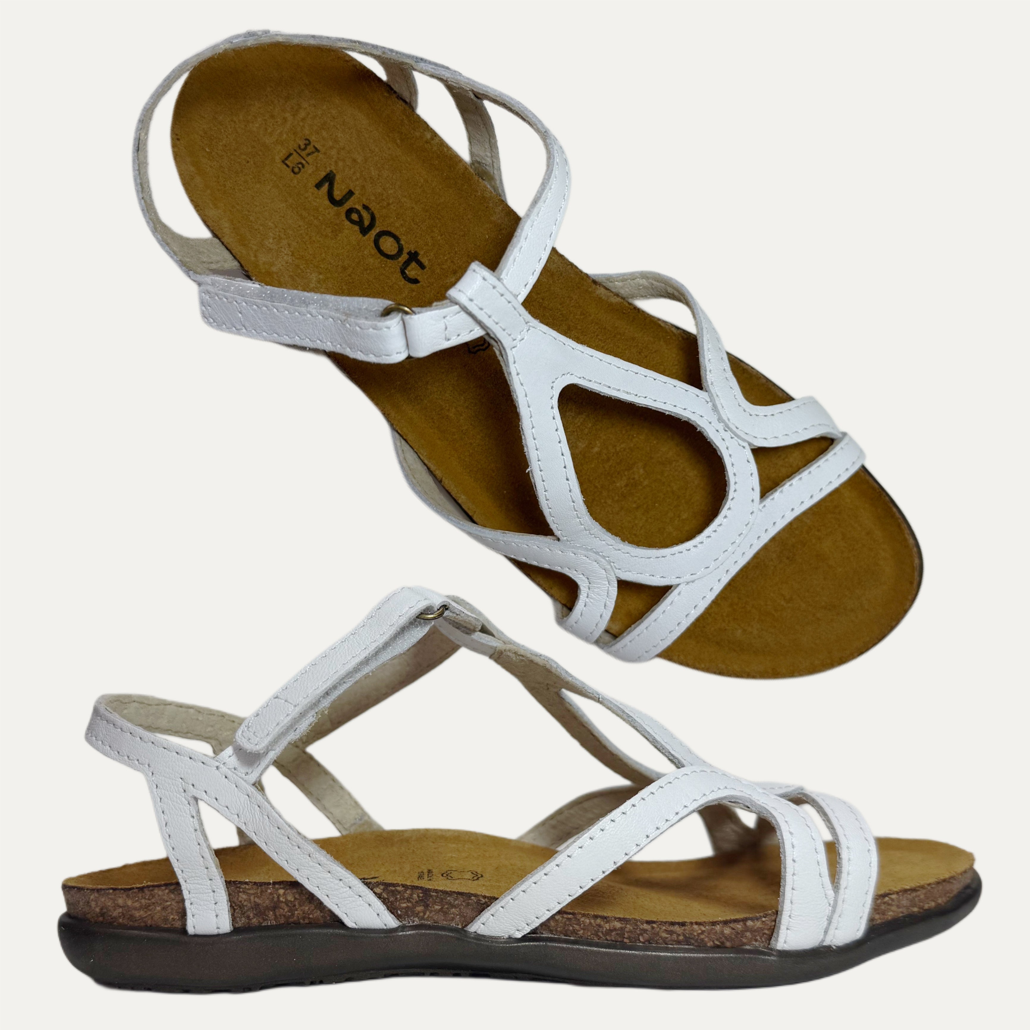 Pair of white sandals with brown soles on a light gray background