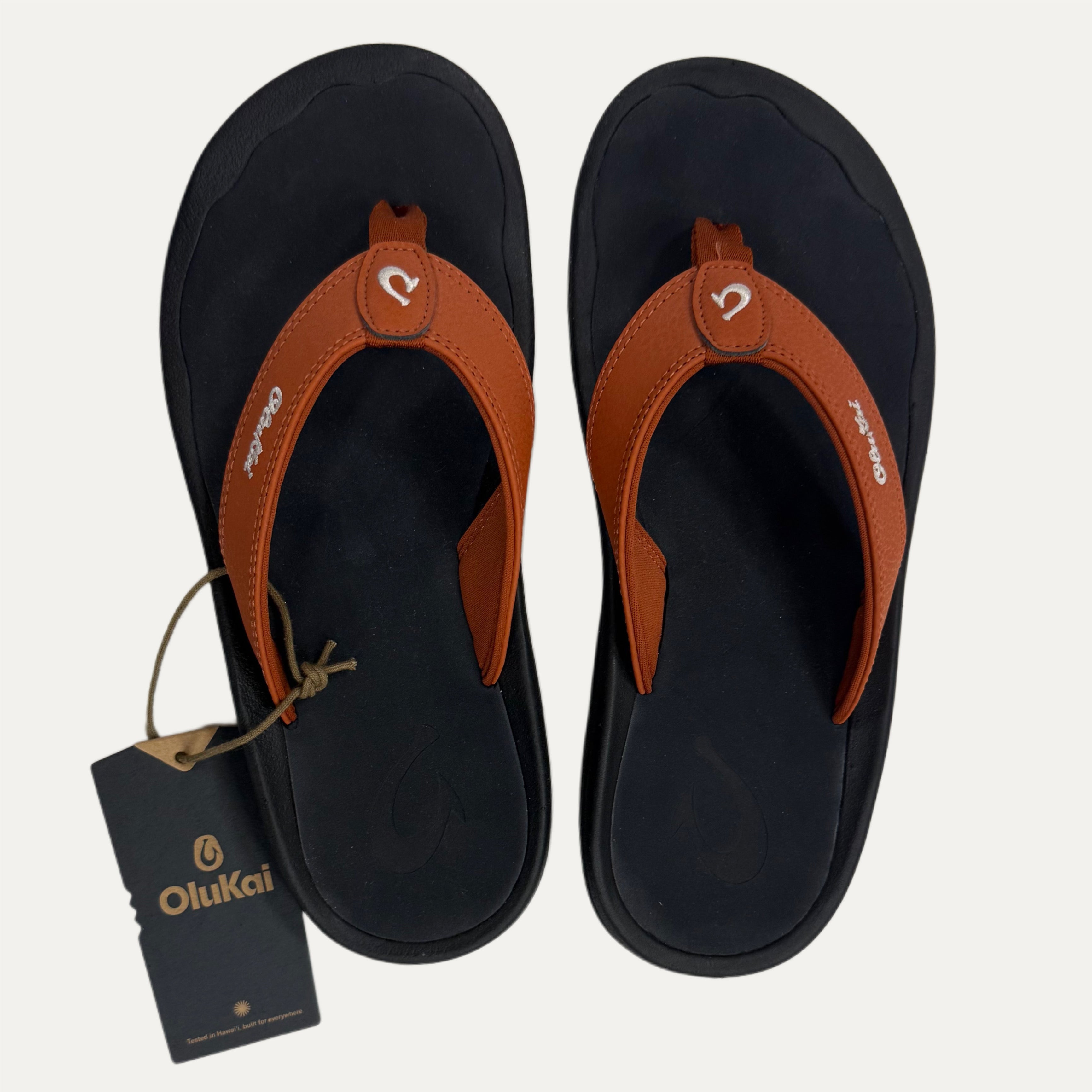 Burnt orange flip flop and a visible brand tag on a white background