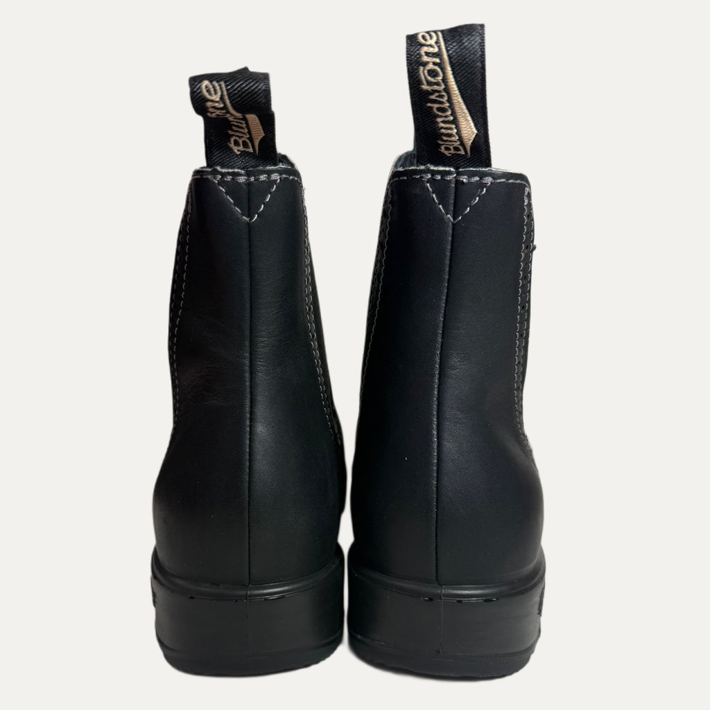 Pair of black leather boots with brand labels on a white background