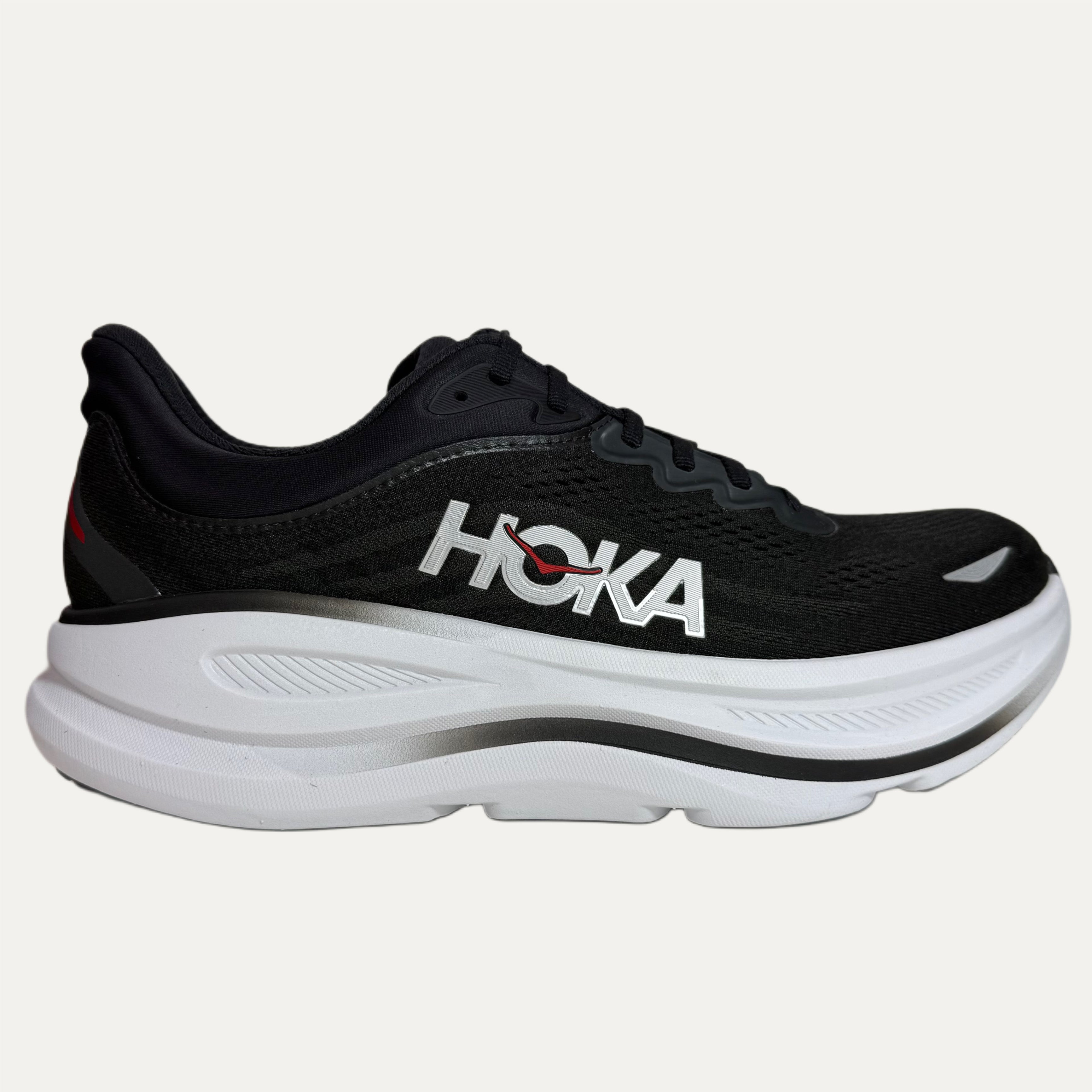 Black running shoe with white sole on a light gray background