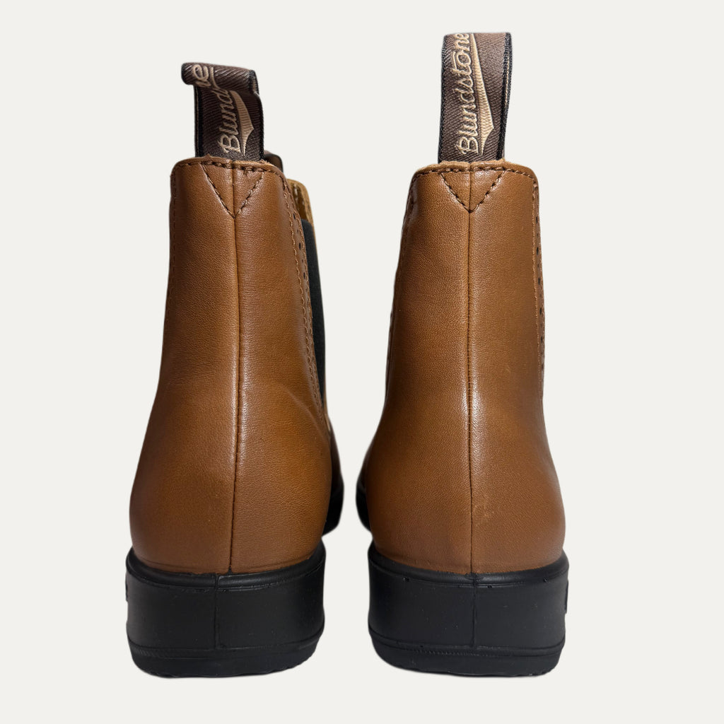 Pair of brown leather boots with black soles on a white background
