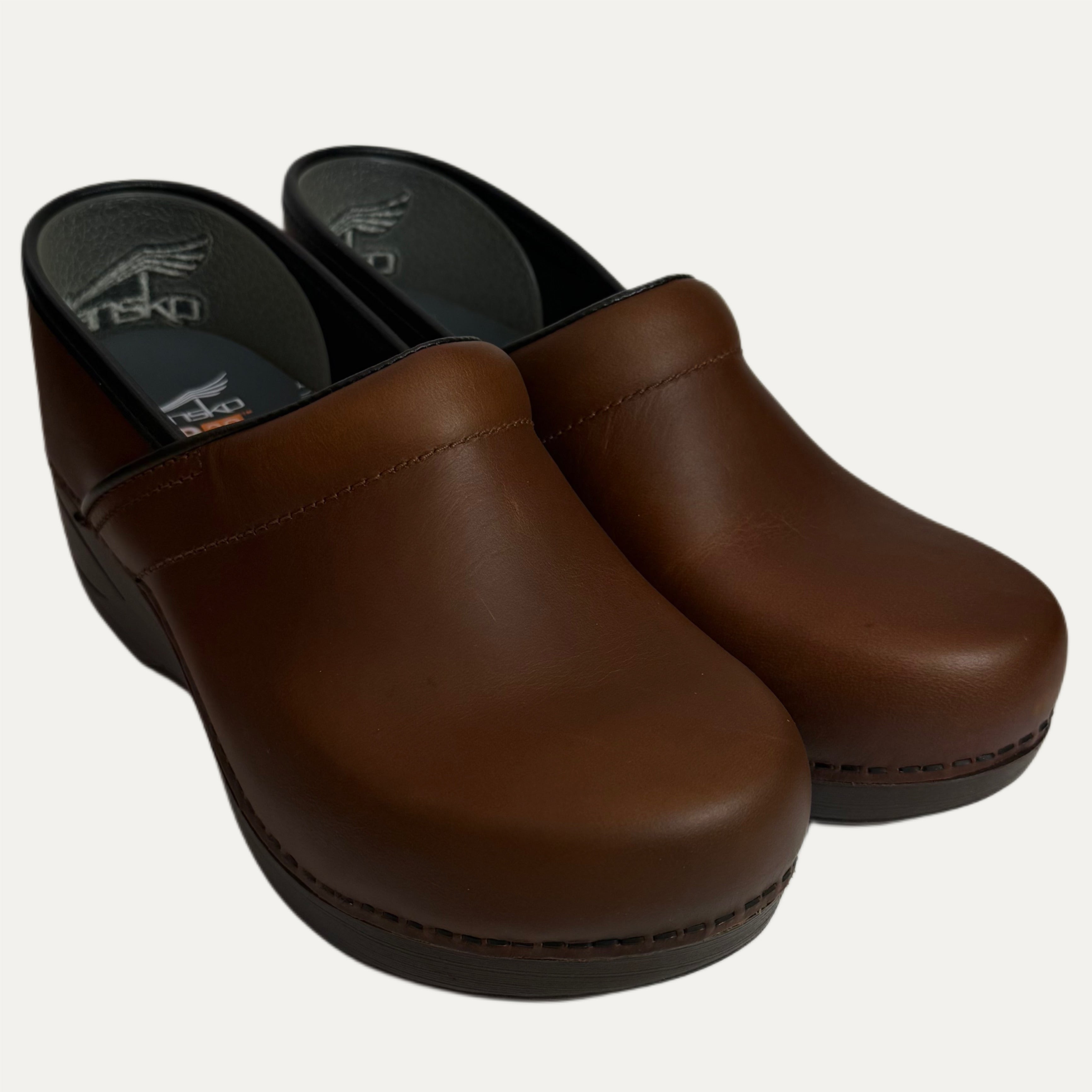 Pair of brown leather clogs on a white background