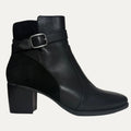 Black ankle boot with a buckle on a light gray background